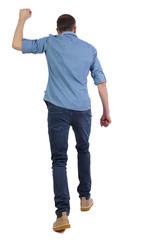 Fototapeta premium Back view of a man who goes and swings his fist.