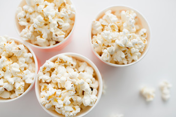 fast food, junk-food and unhealthy eating concept - close up of popcorn in disposable paper cups from top