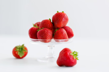 fruit, food and berries concept - strawberries on glass stand over white background