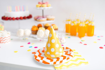 birthday and festive concept - party caps, food and drinks on table