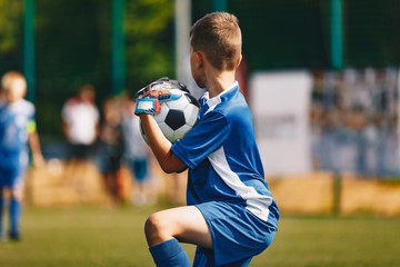 Young Soccer Goalie Goalkeeper Catching Ball. Young Boy Soccer Goalie. Soccer Game on Sunny Summer Day. Sport Activities for Children. Football Match in the Background. Youth Sport Wallpaper