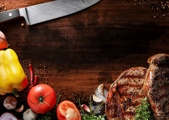 Fresh beef steak on the old wood desk. Around are fresh tomatoes in drops of water, sweet and spicy...