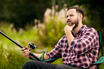 leisure and people concept - bearded fisherman with fishing rod