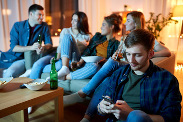 technology, internet addiction and people concept - man with smartphone at home friends party in evening