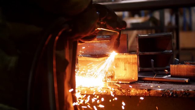Construction plant. A man working with a welding machine. Making notches on an iron detail