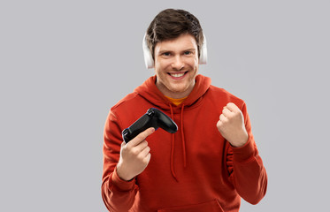 technology, gaming and people concept - young man or gamer in headphones with gamepad playing video...