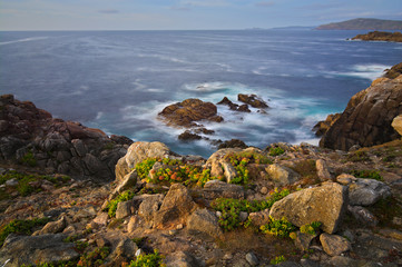 atardecer en la costa con un mar en movimiento y las rocas iluminadas