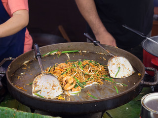 Stir fried instant noodle with shrimps and green onion, bean sprouts in wok.