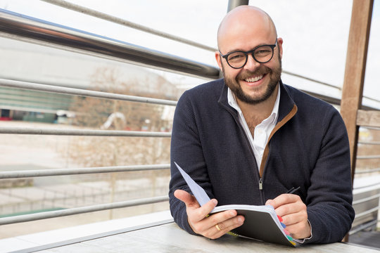 Happy middle-aged man making notes in street cafe