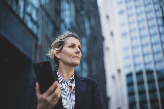 Businesswoman walking in city using smartphone