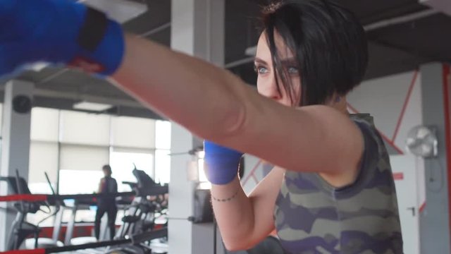 Fit short hair brunette woman boxing in sportswear. Female boxer training hard, slow motion