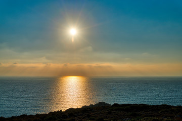 sunset over the sea with rocks in front
