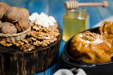 healthy food. Baked apples with cottage cheese and nuts lie in a black baking dish on a blue wooden table