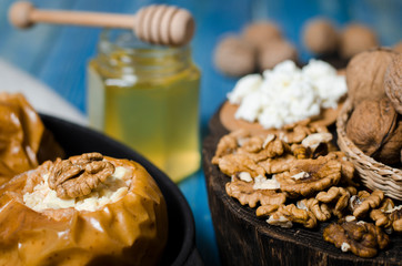 healthy food. Baked apples with cottage cheese and nuts lie in a black baking dish on a blue wooden table