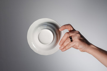 Male hand holding a white plate, on a light background. bottom view