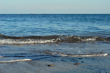 Rocky coast of the sea. Waves on the beach. Blue sea water.