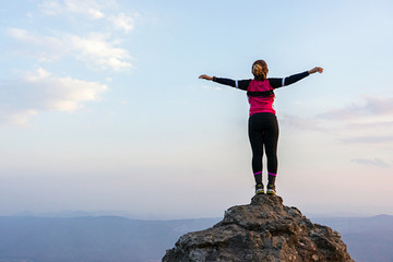 Woman standing on rock cliff with horizon and sky background