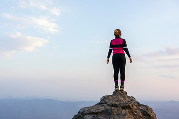 Fototapeta na wymiar Asian woman in sportswear standing on high rock cliff