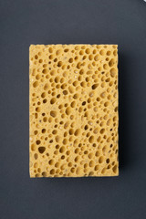 Close up view of cleaning sponge, mesh structure pattern on black surface. Yellow sponge close-up shot.