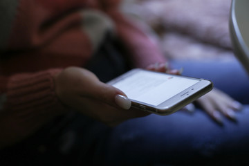 Mockup image of woman's hands holding white mobile phone with blank screen on thigh