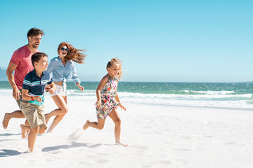 Happy family running on beach - Powered by Adobe