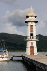 Fototapeta na wymiar White lighthouse on the fishing pier at the tropical Koh Chang Island, Thailand.