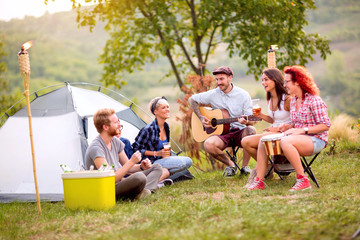Group of young people relaxing in front of tent outdoor