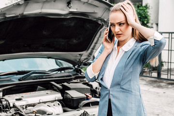 Woman calling for assistance with broken down car engine on street