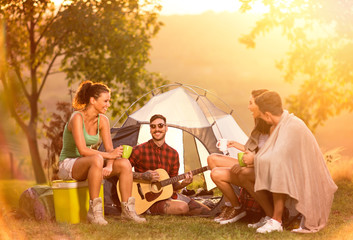 Group of campers next tent having fun with guitar