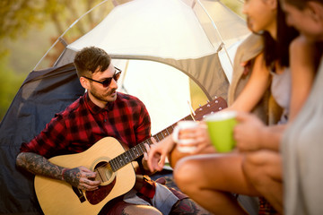 hipster man with guitar on camping trip
