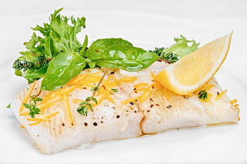 Organic white fish fillet cooked with fresh green salad leafs and lemon