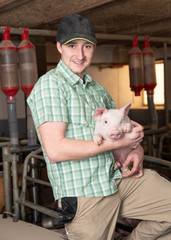 junger Landwirt mit Ferkel im Stall, Schwein © FotoSabine