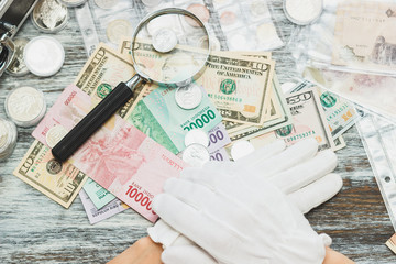 Hands in white gloves, different American dollars and Indonesian rupiahs, numismatics concept