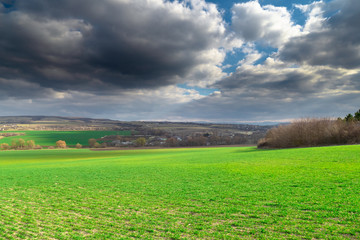 Landscape with green field and blue sky with dark clouds
