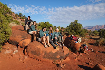 Backpacking family resting on a boulder on Horseshoe Mesa in Grand Canyon National Park, Arizona.