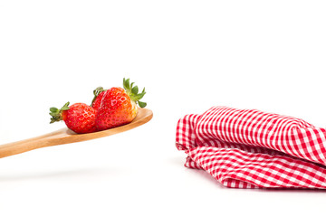 Fresas con cuchara de madera y servilleta roja sobre fondo blanco aislado. Vista de frente. Copy space