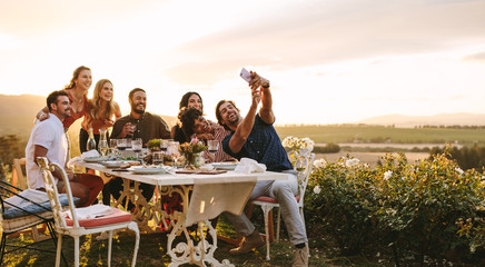 Group of friends taking selfie at dinner party - Powered by Adobe