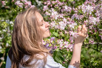 Fototapeta premium Beautiful woman among blooming apple trees in spring garden