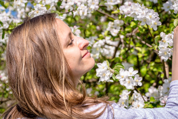 Fototapeta premium Beautiful woman among spring blossoms in the garden