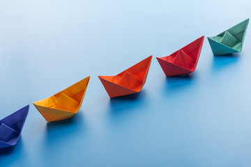 Colorful bright paper boats on light blue surface