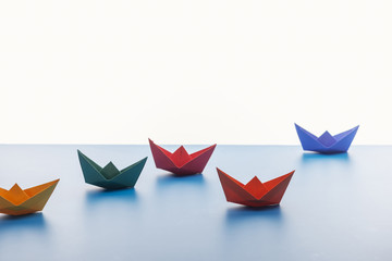 Colorful paper boats on light surface on white background