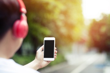 young man holding hand smart phone using earphone  to listening to music with isolated copy space empty screen for changes song and tracks on mobile. headphone Enjoying the rhythm. technology concept 