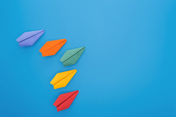 Flat lay with colorful paper planes on blue surface