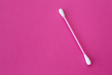 pink cotton buds with white heads laid out on a pink background