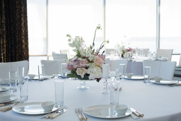 Event white restaurant table served and decorated with delicate fresh flowers