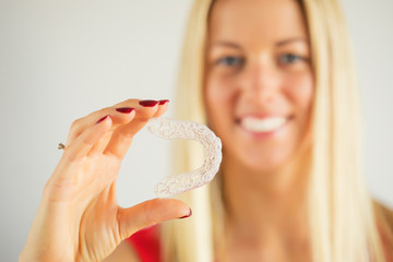 Woman with beautiful smile holding teeth whitening tray