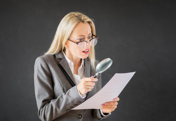 Woman reading business contract with magnifying glass