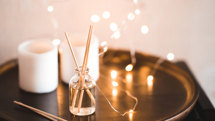 Aroma sticks with glass bottle over glowing lights at background. Home fragrance.