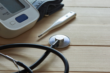 A stethoscope, sphygmomanometer and thermometer on wooden background