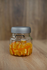 Closed glass mini bottle with sliced orange fruit. Wooden background